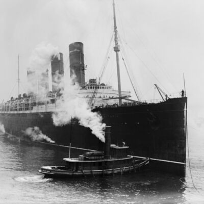 HRM Lusitania steered by tug boats at a New York City pier. Mar. 6, 1914.
